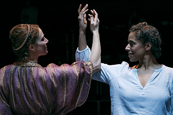 Pericles in simple white shirt dances with upraised arm to arm opposite Thaisa wearing a coronet and purple striped robe